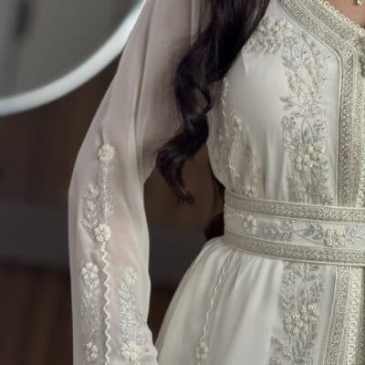 Elegant bridal dress with intricate silver embroidery and embellishments from Taj Al Mahaa.
