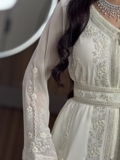 Elegant bridal dress with intricate silver embroidery and embellishments from Taj Al Mahaa.