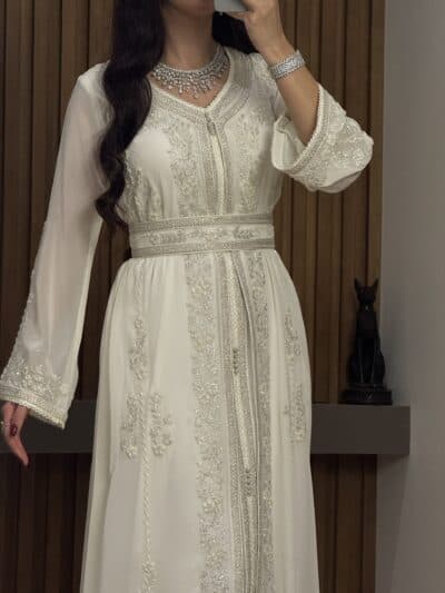 Elegant white embroidered kaftan with silver beadwork, perfect for special occasions and celebrations at Taj Al Mahaa.