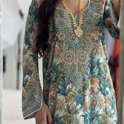 Vibrant floral embroidered traditional dress with gold jewelry for special occasions.