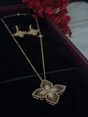 Gold butterfly pendant necklace and matching earrings with diamond accents on black velvet display.