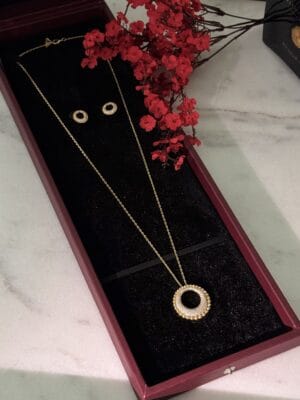 Elegant gold jewelry set with circle pendant and matching earrings, beautifully displayed in a gift box.