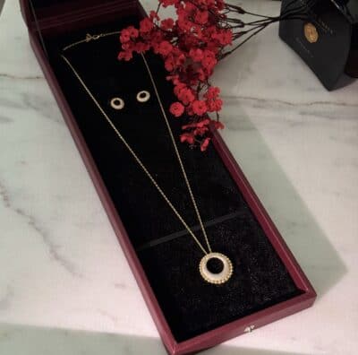 Elegant gold jewelry set with circle pendant and matching earrings, beautifully displayed in a gift box.