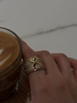 Gold and diamond ring on finger near a cup of coffee, luxury jewelry, elegant accessory, TAJ ALMAHA.