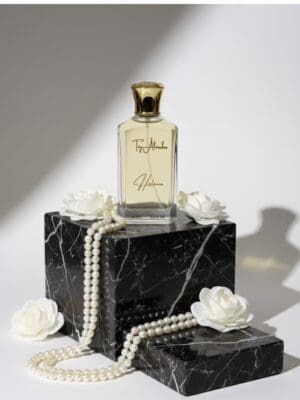 Elegant perfume bottle with "Taj Al Maha" inscription on a marble pedestal, surrounded by pearls and white flowers.