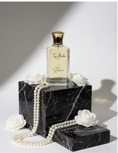 screenshot-4 Elegant perfume bottle with "Taj Al Maha" inscription on a marble pedestal, surrounded by pearls and white flowers.